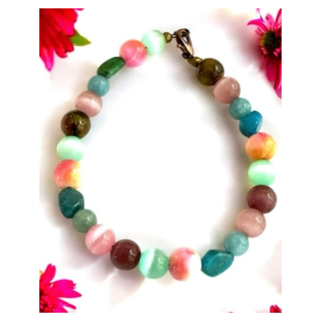 Treasures of the Willow Cove gemstone bracelet displayed on a bright white background with colorful flowers framing the earth and sea-inspired beads.