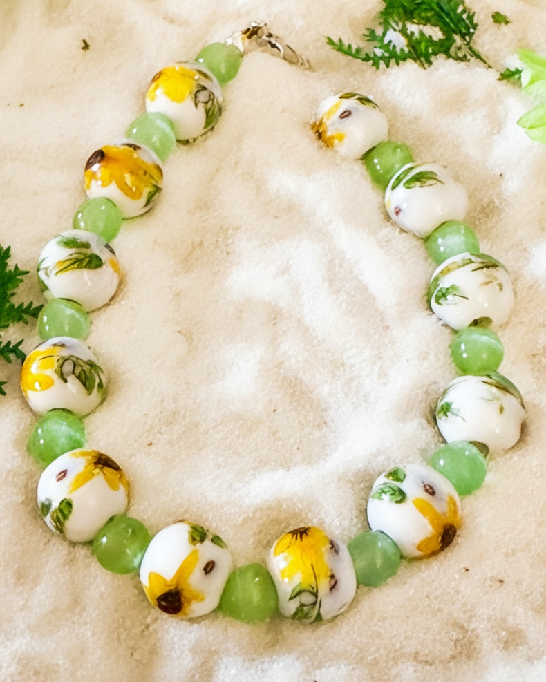 Wildflower Sunlight sunflower bracelet arranged on sand with nature-inspired styling.
