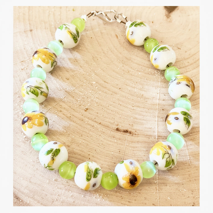 Sunflower garden bracelet displayed on a natural wood slice with floral-inspired porcelain beads.