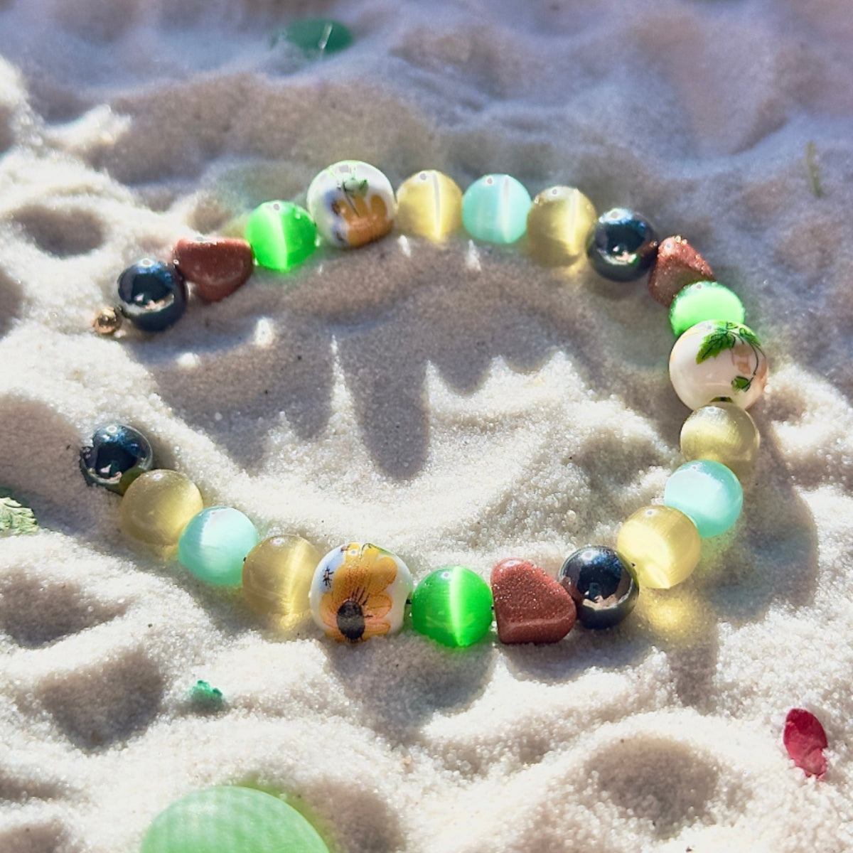 Willow Garden beaded bracelet on a sandy surface with leaf floral surroundings