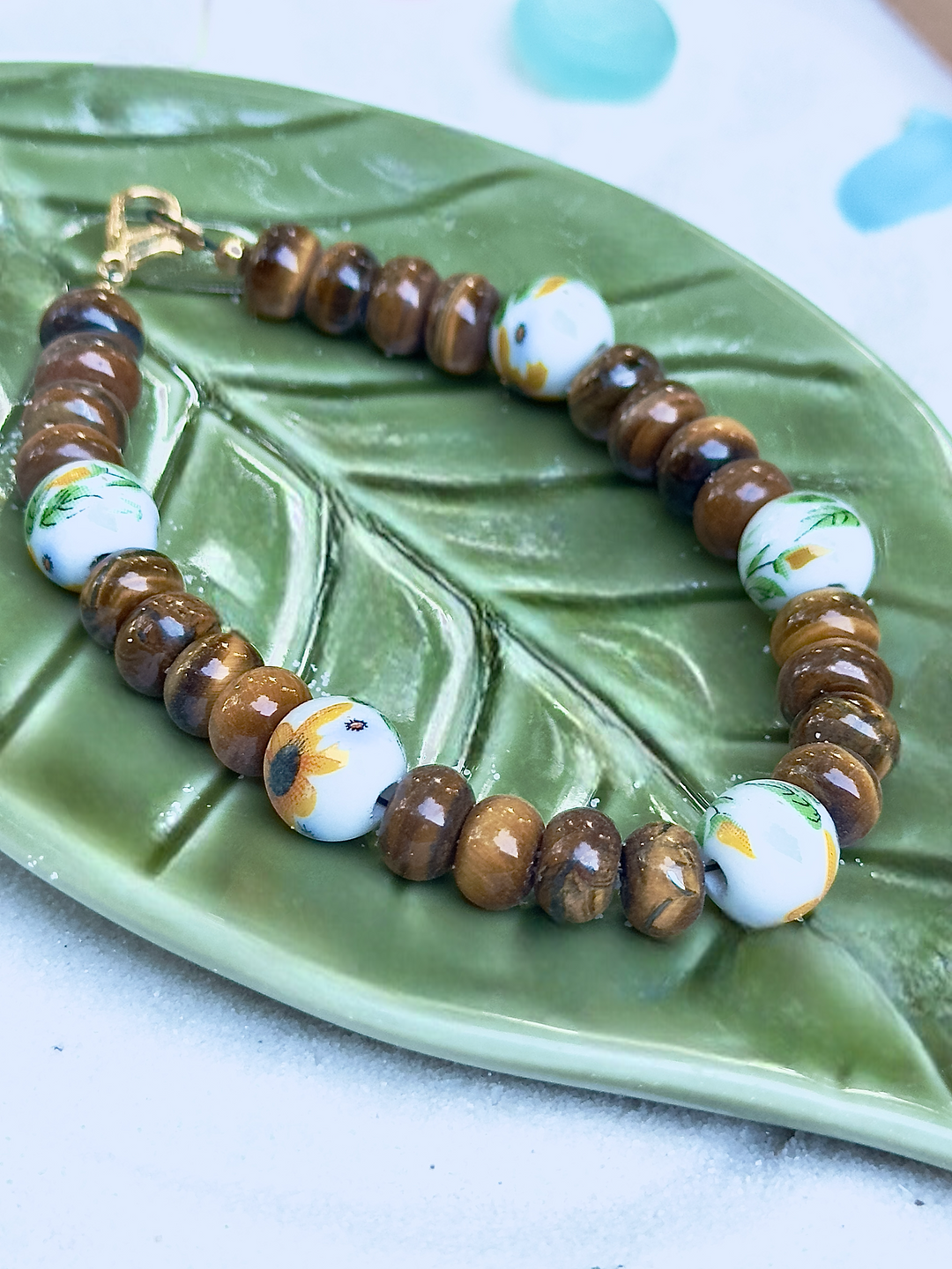Bracelet with brown and white beads on a green leaf-shaped dish