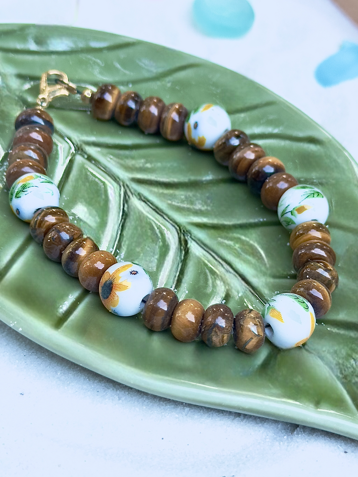 Bracelet with brown and white beads on a green leaf-shaped dish