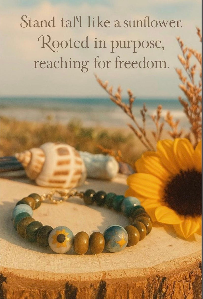 Sunflower, bracelet, and seashell on a wooden surface with a beach background and motivational quote.