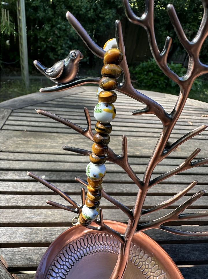 Decorative metal piece with beads and a bird on a wooden surface