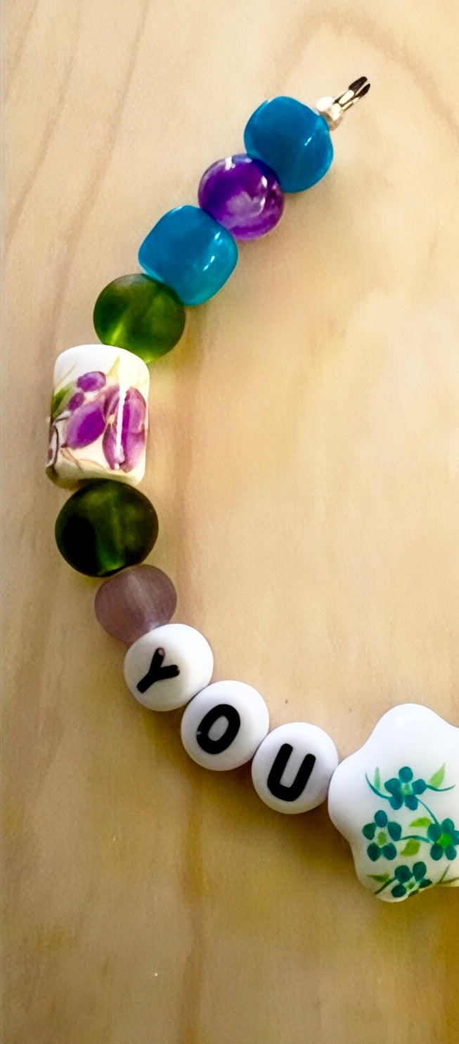 Colorful beaded bracelet floral designs on a wooden surface