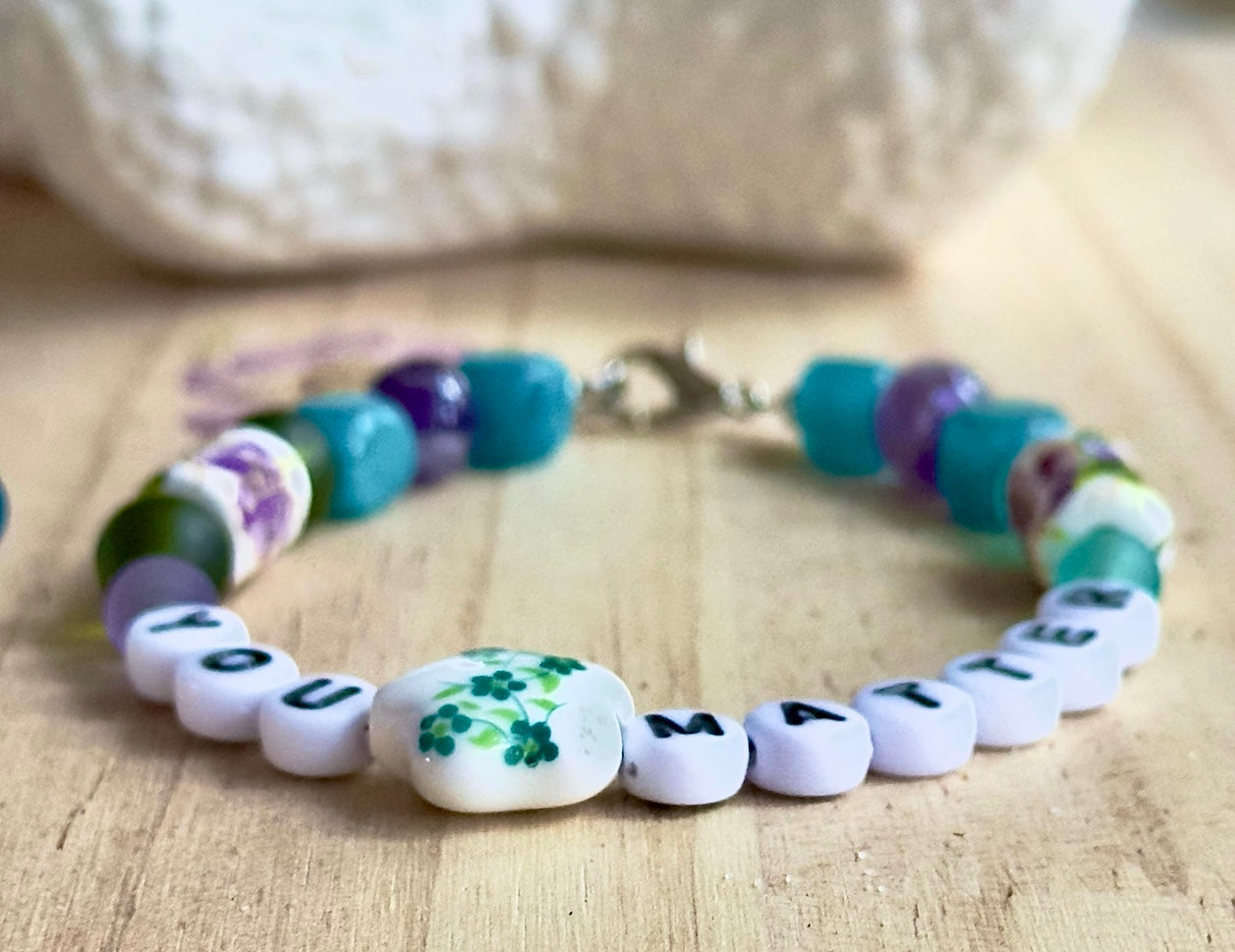 Colorful beaded bracelet with letter beads on a wooden surface