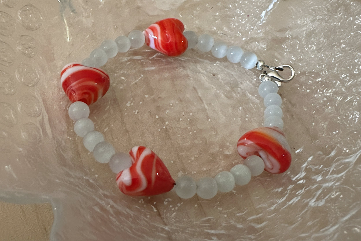 Glass heart bead bracelet arranged inside a clear textured dish showing full bracelet design.
